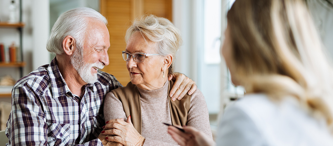 SLIDER_Beratung_Begleitung Älteres Ehepaar schaut sich liebevoll an, im Vordergrund eine Frau